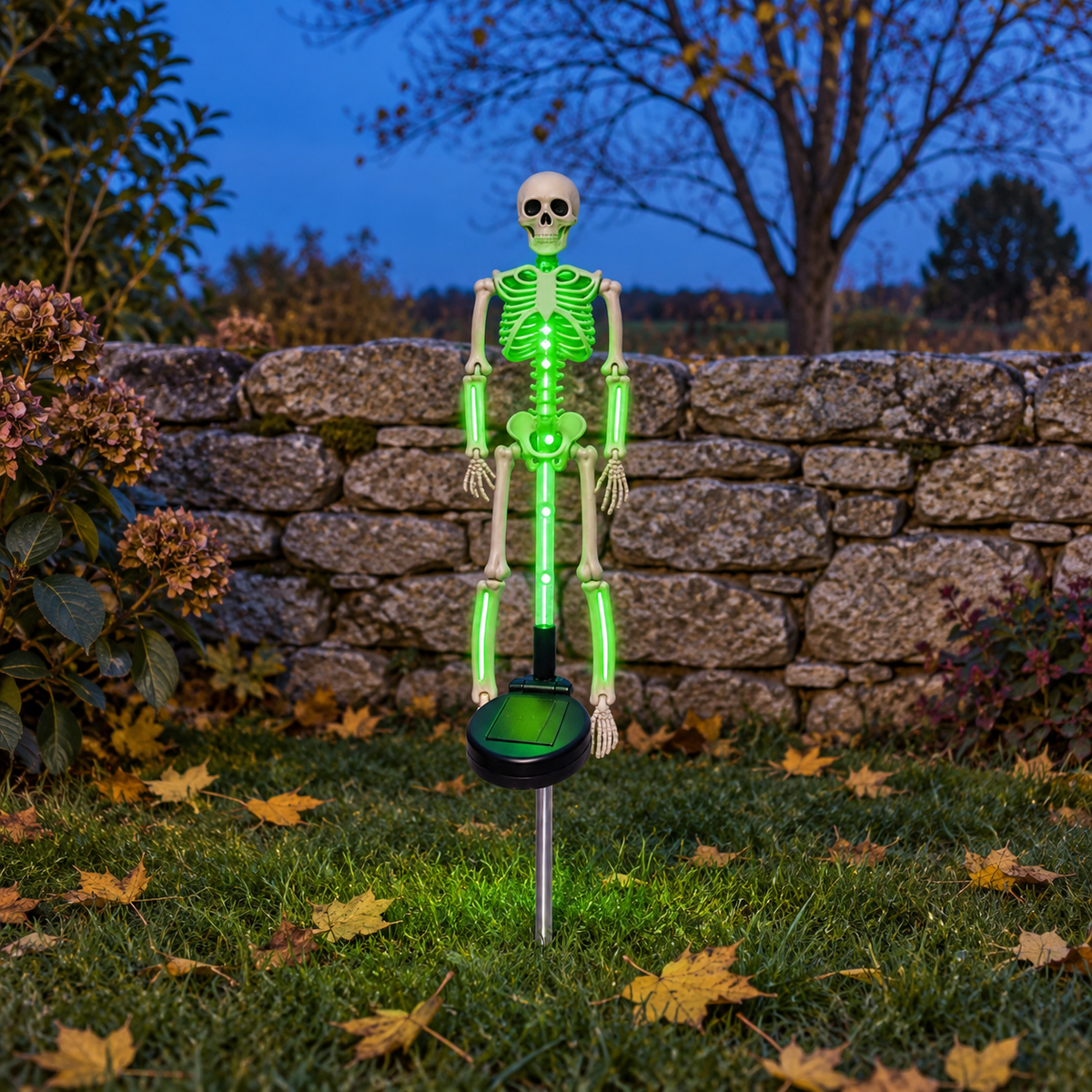 Green solar skeleton stake light glowing on a lawn in front of a stone wall at dusk