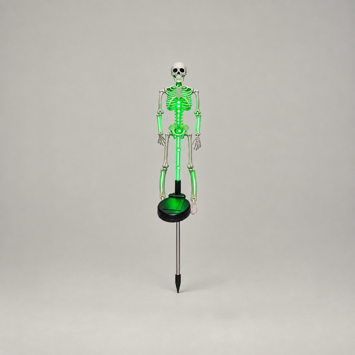 Green solar skeleton stake light glowing, shown whole from skull to stake tip on a plain gray background