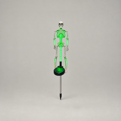 Green solar skeleton stake light glowing, shown whole from skull to stake tip on a plain gray background