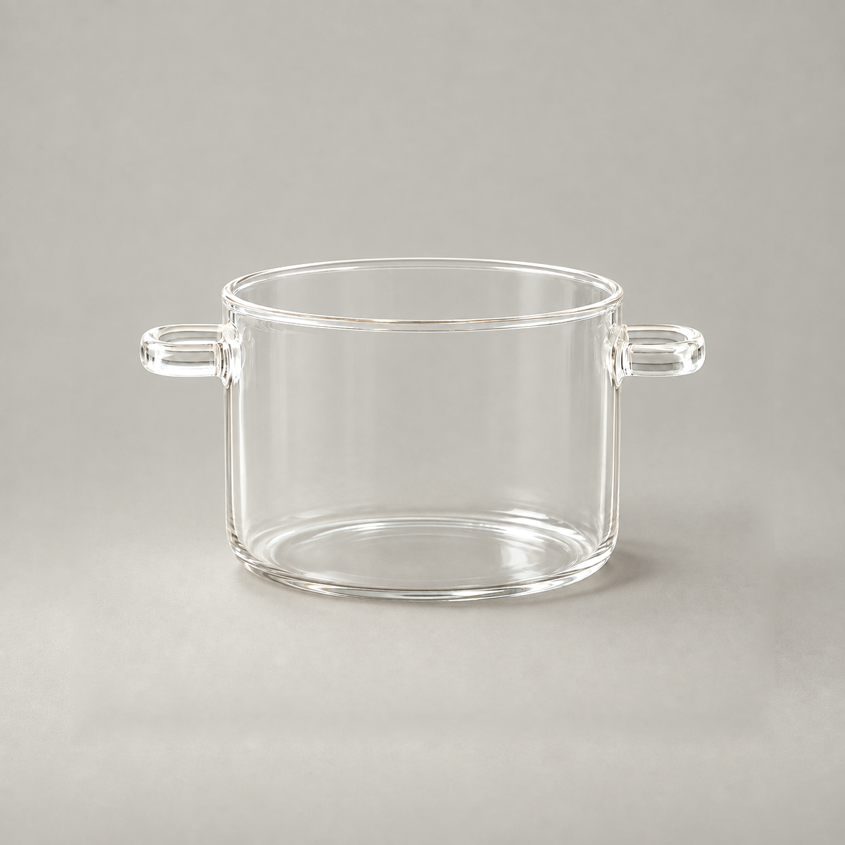 Glass cooking pot without its lid, showing the rounded rim bead, straight clear wall and two open loop handles