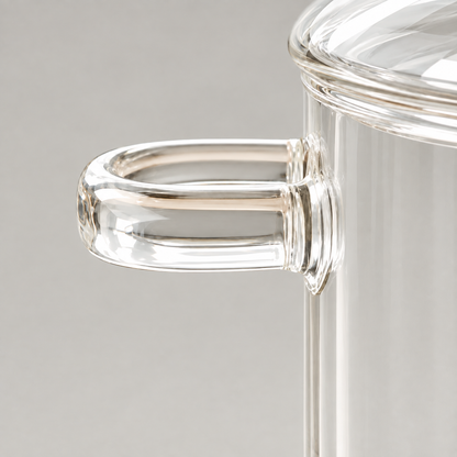 Close up of a solid glass loop handle joined to the side of a glass pot just below the lid