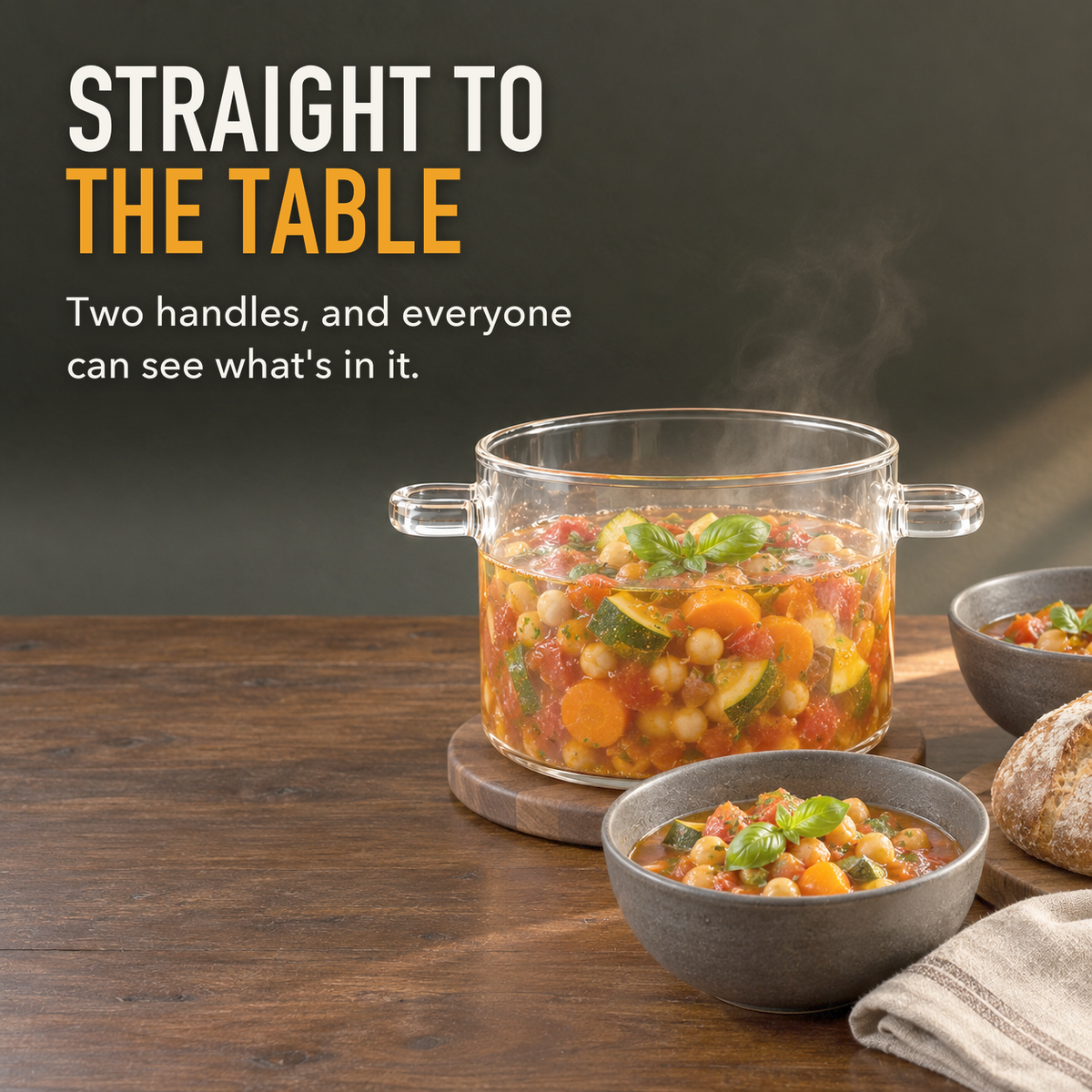 Glass cooking pot of vegetable stew on a walnut trivet at a dining table with two bowls, with the words Straight To The Table