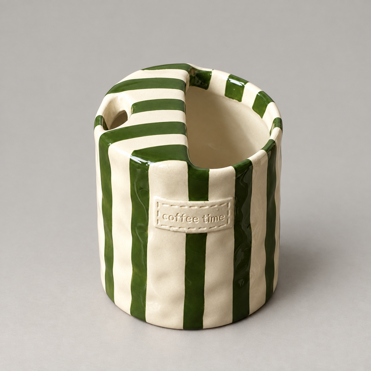 Green striped ceramic cup seen from above, showing the folded top and its round straw hole