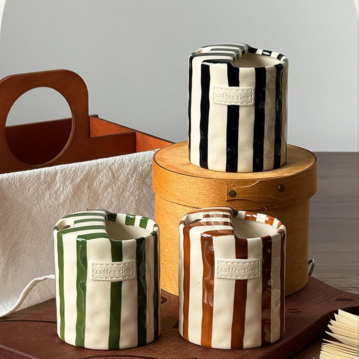 Black, green and brown striped ceramic cups with coffee time labels on a wooden box and board