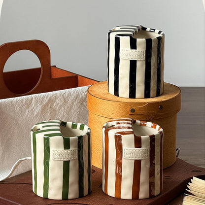 Black, green and brown striped ceramic cups with coffee time labels on a wooden box and board
