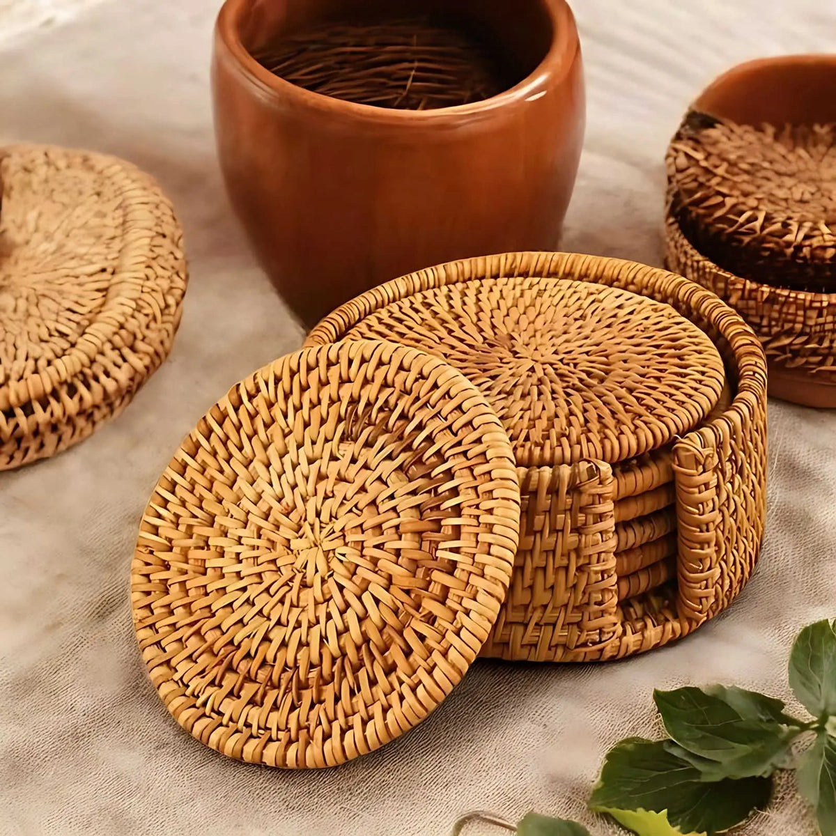Woven rattan coasters in their round holder, with one coaster leaning against the side