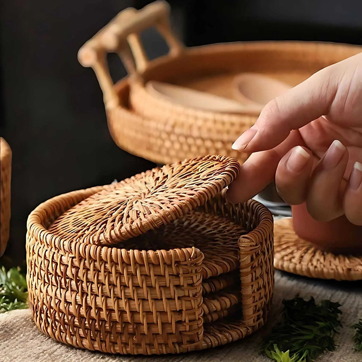 Hand lifting a woven rattan coaster out of the round holder