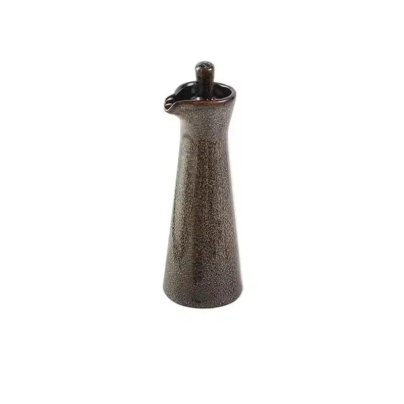 Brown speckled ceramic oil dispenser with a matching glazed stopper, standing alone on a white background