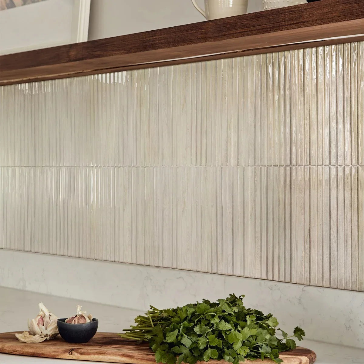 Pale wood grain peel and stick backsplash tiles in slim vertical strips on a kitchen wall between a walnut shelf and a white stone counter