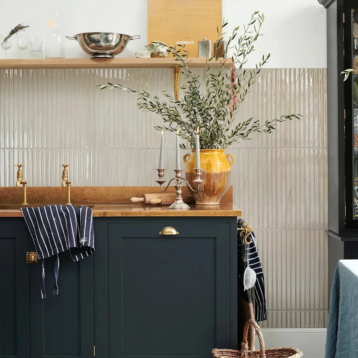 Wood grain look strip tiles covering a kitchen wall behind navy shaker cabinets and a copper counter, running from the shelf down to the floor