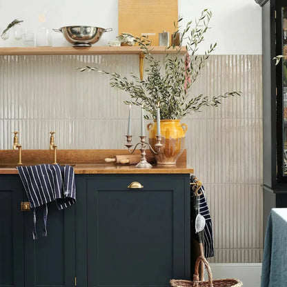 Wood grain look strip tiles covering a kitchen wall behind navy shaker cabinets and a copper counter, running from the shelf down to the floor