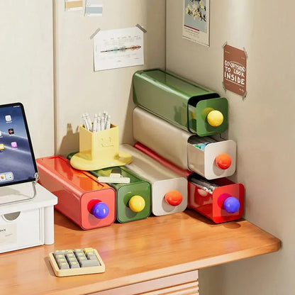 Red, green and white storage drawers stacked on a desk beside a tablet, two drawers pulled out