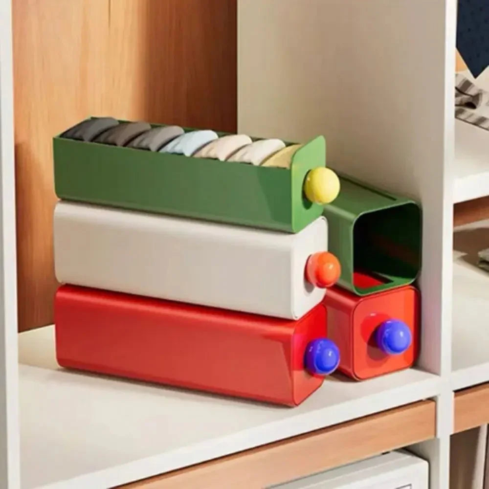 Green, white and red storage drawers stacked on a shelf, the green tray pulled out holding rolled socks