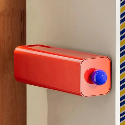 Red storage drawer with a blue ball knob mounted on a wardrobe panel