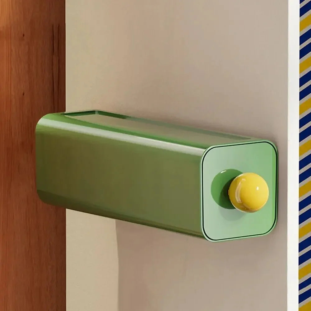 Green storage drawer with a yellow ball knob mounted on a wardrobe panel