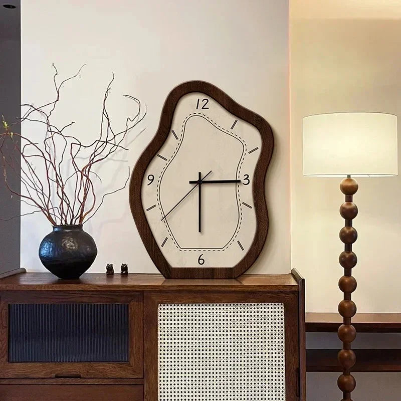 Wavy wall clock with a wood-grain frame and a cream face standing on a walnut sideboard beside a floor lamp