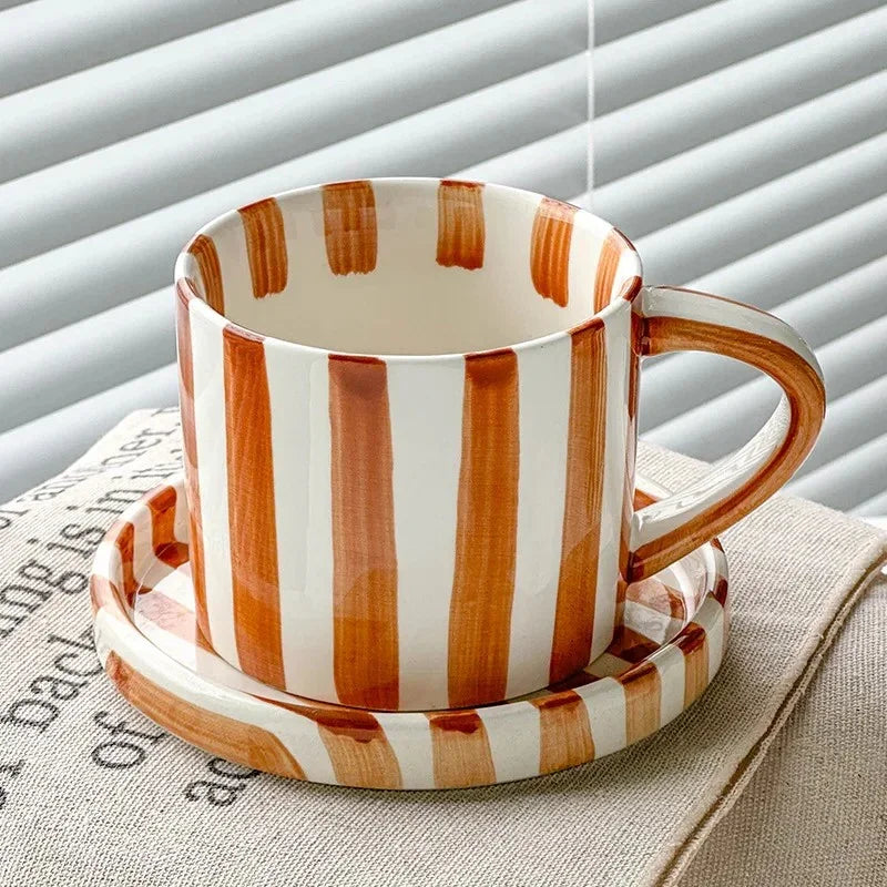 Caramel brown striped ceramic cup on its matching saucer, by a window with blinds