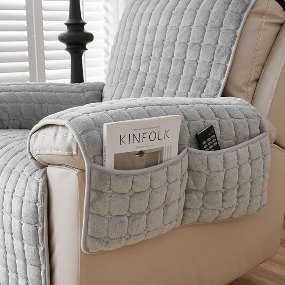Gray quilted arm cover with a two-compartment pocket holding a magazine and a remote