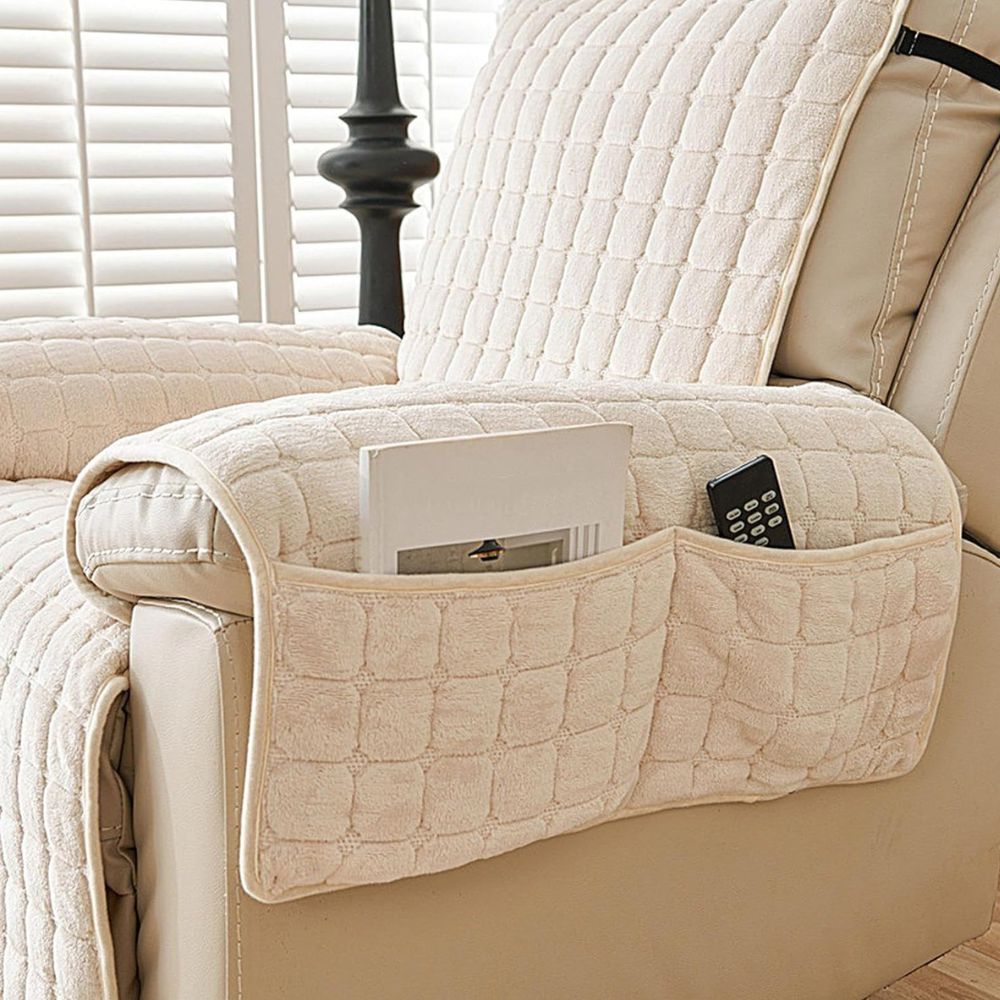 Beige quilted arm cover with a two-compartment pocket holding a magazine and a remote