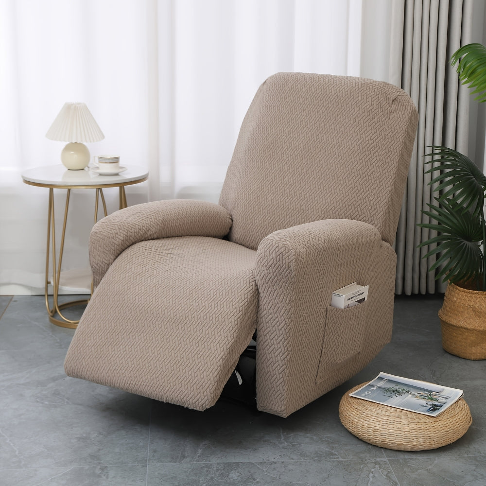 Taupe stretch recliner cover on a single recliner beside a rattan pouf with a magazine