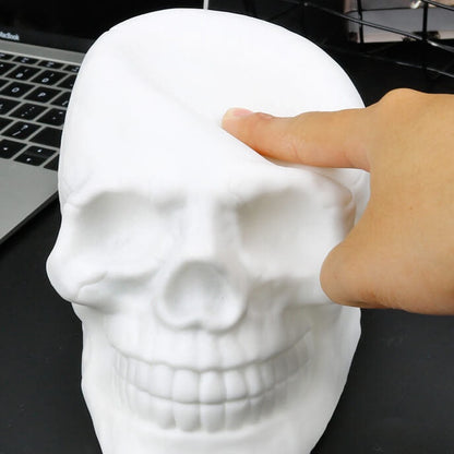 A finger pressing into the soft white silicone top of the skull night light