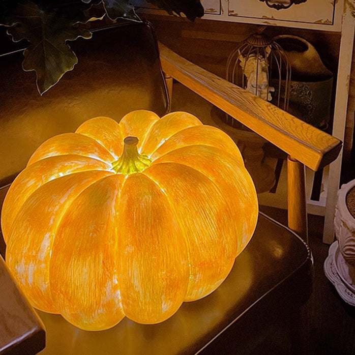 Solar pumpkin light glowing warm amber through its ribbed resin shell, set on a wooden armchair