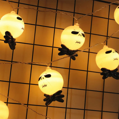 Lit string light heads with black bow ties hanging from a clear wire in front of a black wire grid