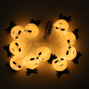 Ten lit string light heads with black bow ties laid in a loop around a clear battery box