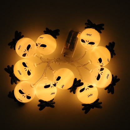Ten lit string light heads with black bow ties laid in a loop around a clear battery box