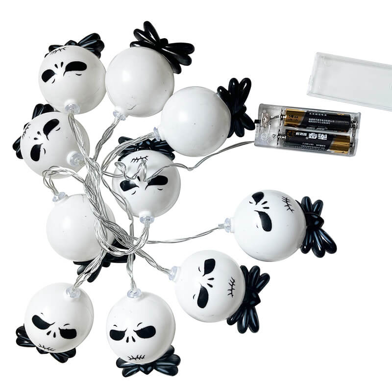 Ten unlit white string light heads with black bow ties on a clear twisted wire, beside an open clear battery box holding two AA batteries