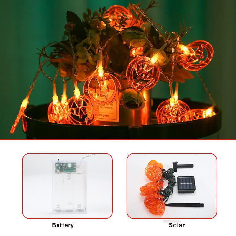 Pumpkin string lights around a planter, with the clear battery box and the solar panel, stake and wire shown below