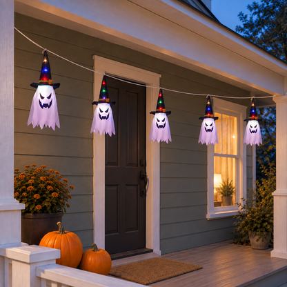 Five fabric ghost lights in black witch hats glowing along a front porch beam at dusk