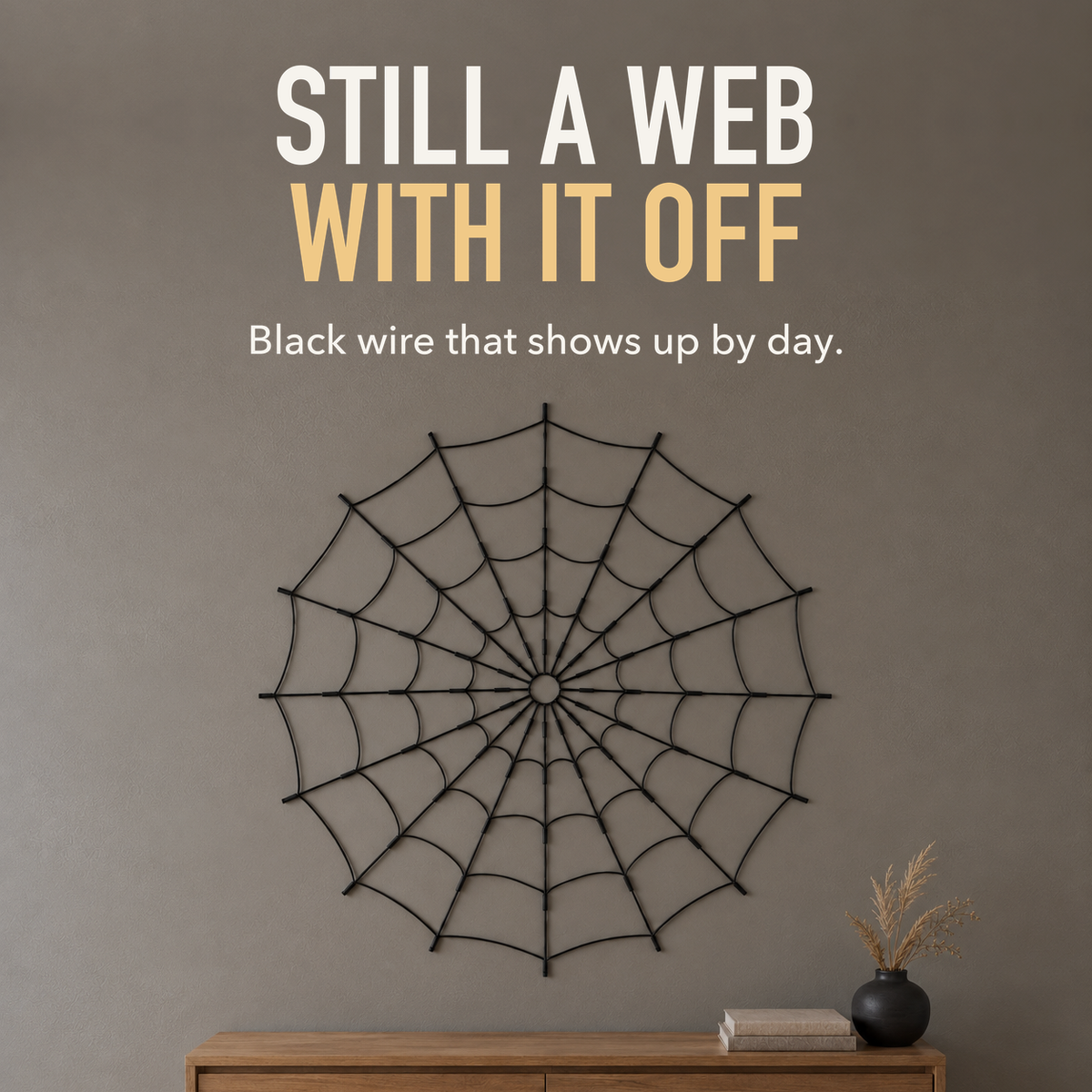 Text image: Still a web with it off. Unlit black wire spider web hanging on a stone grey wall above an oak console in daylight