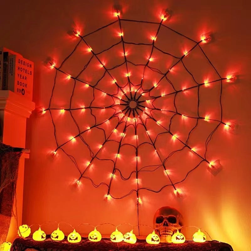 Orange lit spider web light hanging flat on a wall above a mantel with a skull and pumpkin lights