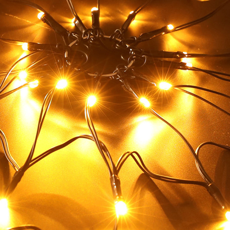 Close view of the lit center of a spider web light, its black wires and glowing LEDs