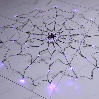 Purple lit spider web light lying flat on a marble floor