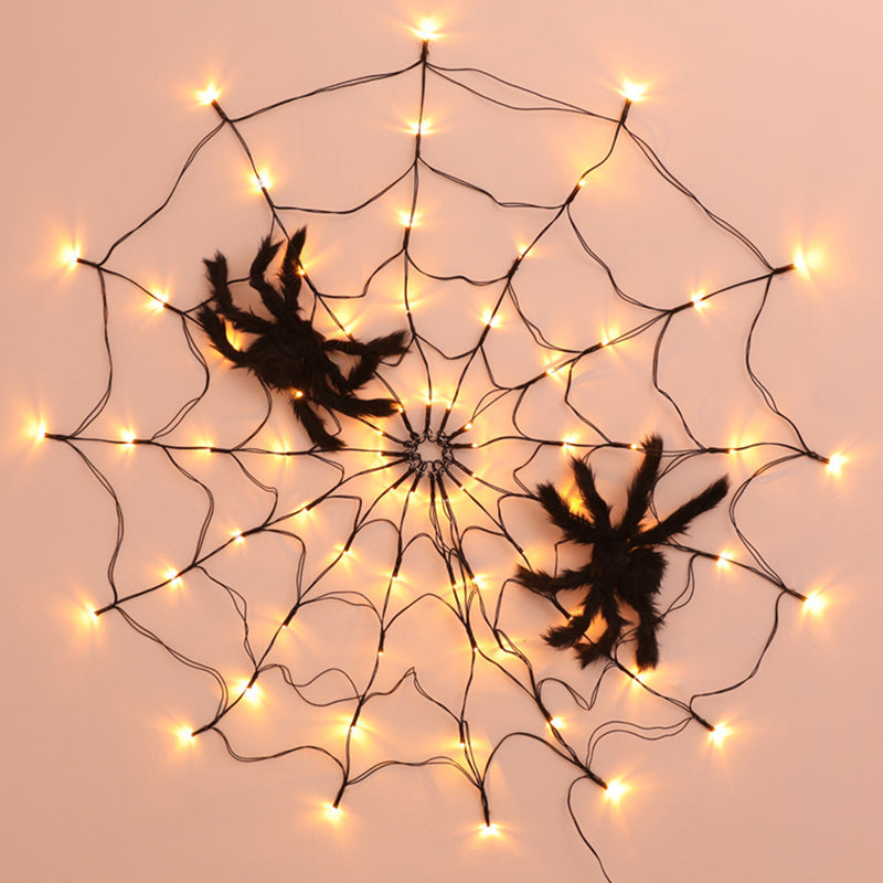Spider web light on a peach wall with two plush spiders