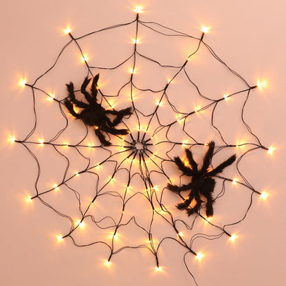 Spider web light on a peach wall with two plush spiders