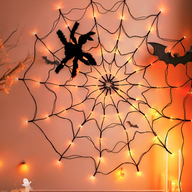 Spider web light on an orange wall with a plush spider and a paper bat