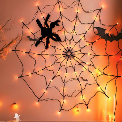 Spider web light on an orange wall with a plush spider and a paper bat