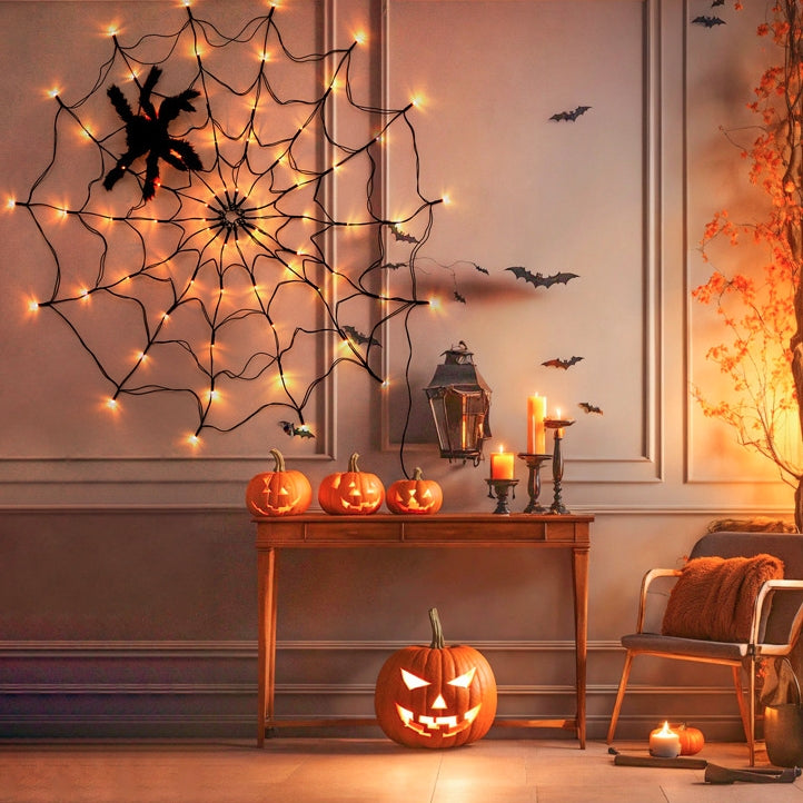 Spider web light on a panelled wall above a console with pumpkins and candles