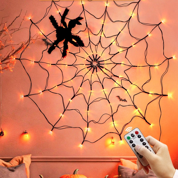 Spider web light on an orange wall with a hand holding a remote control
