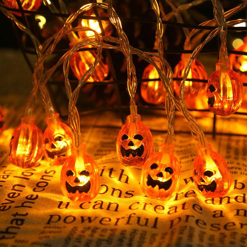 Lit orange jack-o'-lantern bulbs hanging from a clear wire over an open newspaper