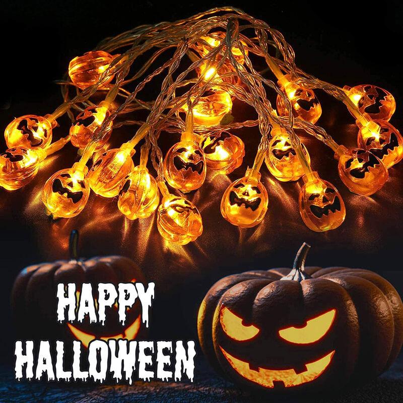 A tangle of lit orange jack-o'-lantern string lights above two carved pumpkins, with Happy Halloween lettering