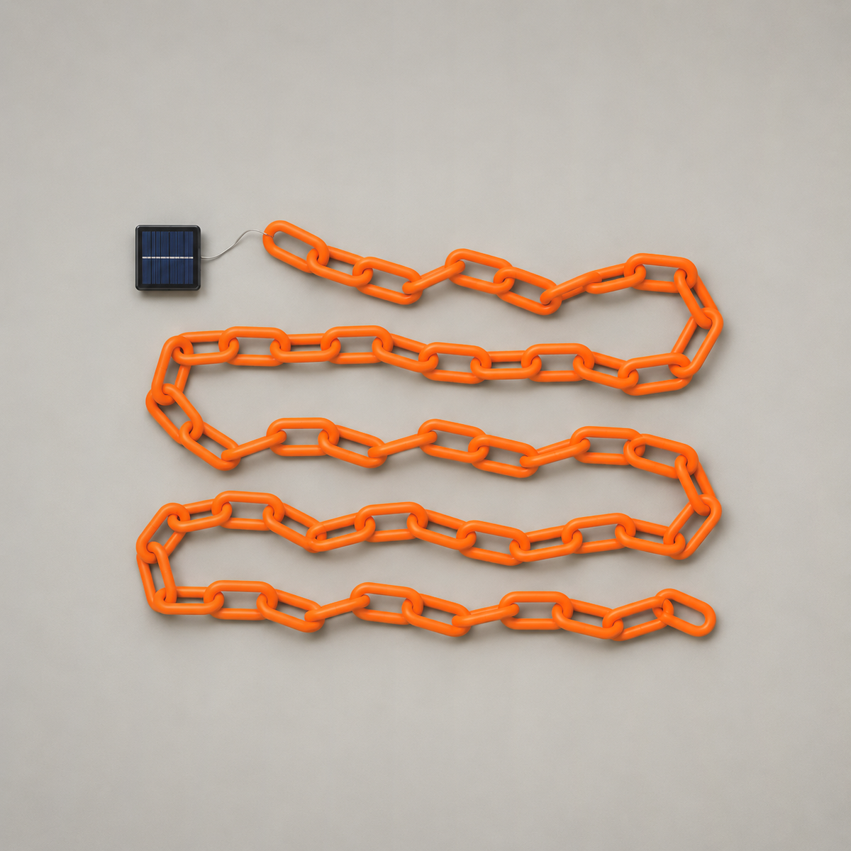 Solar version of the orange chain lights laid out flat with its small solar panel, seen from above on a grey background