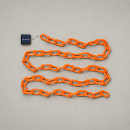 Solar version of the orange chain lights laid out flat with its small solar panel, seen from above on a grey background