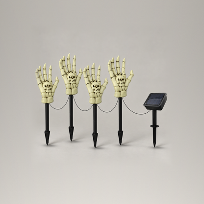 Set of four skeleton hand stake lights with their connecting cable and separate solar panel stake on a plain gray background