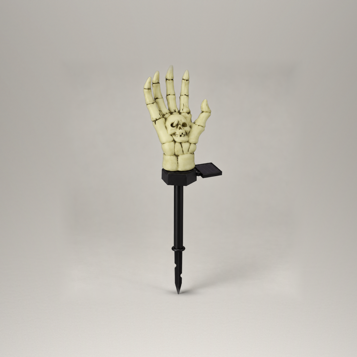Single skeleton hand stake light with its solar panel on the stake collar, shown whole on a plain gray background