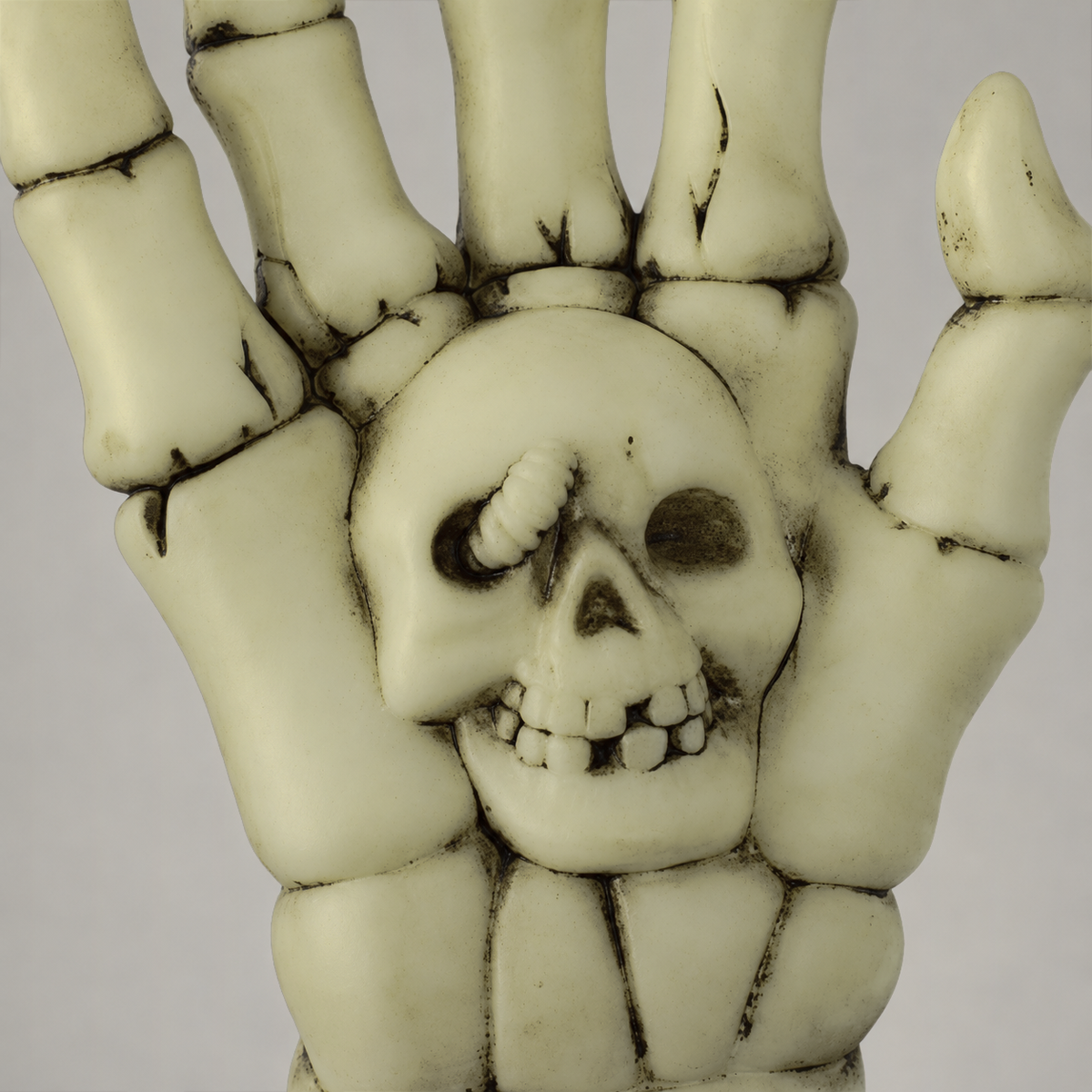 Close-up of the small skull molded into the palm of the skeleton hand, with a grub curling out of one eye socket