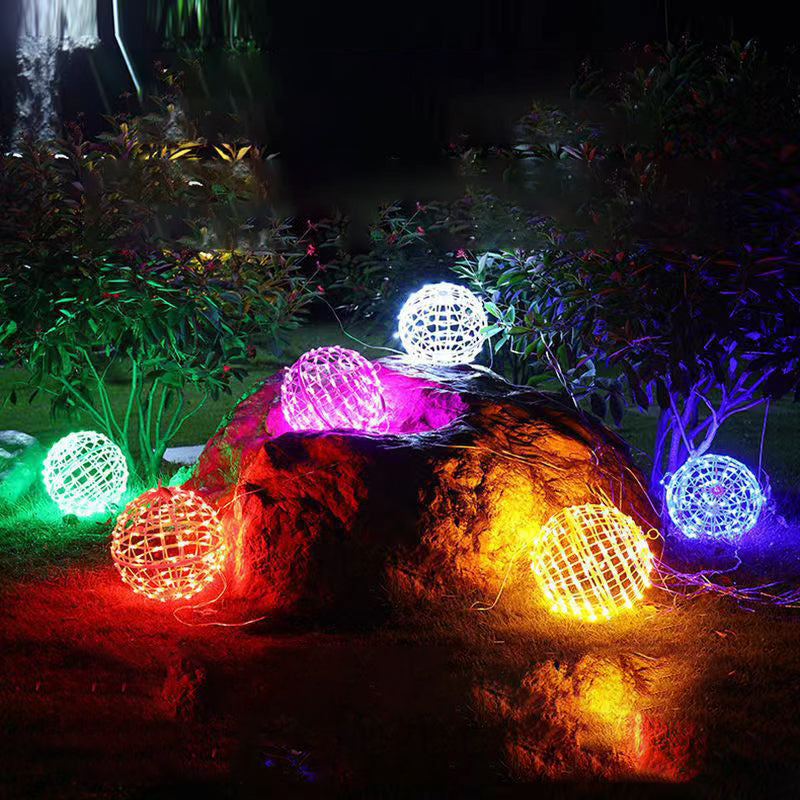 LED ball lights in several colors resting on a garden rock and lawn at night